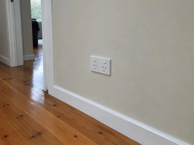White double power point on a painted hallway wall with timber floorboards in Wyong
